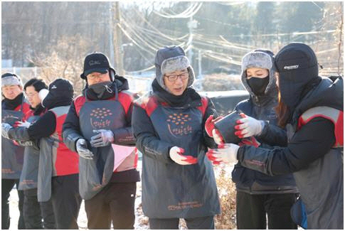 롯데건설 박현철(오른쪽 세번째) 부회장과 배우 정애리(오른쪽 두번째)가 임직원들과 연탄을 나르고 있다. [롯데건설 제공]